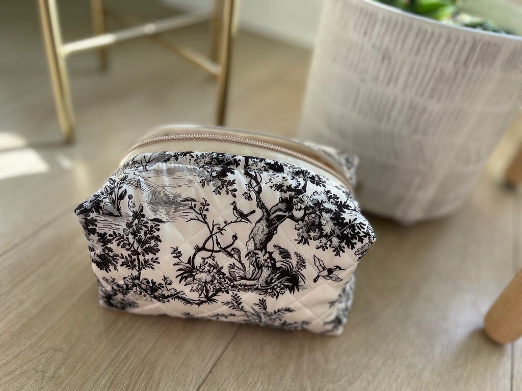 Small pouch with black floral pattern on a wooden surface